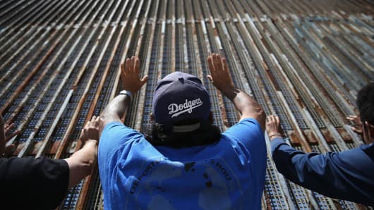 Immigrant advocacy members pray at the U.S.-Mexico border fence on May 1, 2016, in Tijuana.